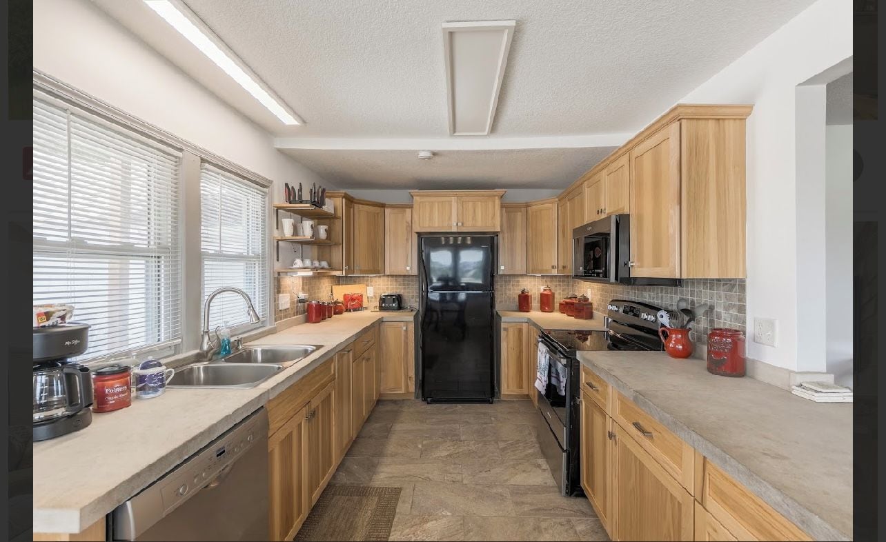 A modern kitchen with wooden cabinets, a black refrigerator, and a microwave.