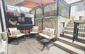 A patio area with wicker furniture, a small table, and a staircase.