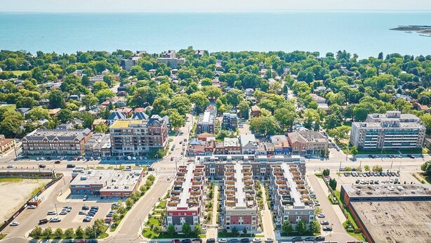 An aerial view of a coastal town with a mix of residential and commercial buildings, a marina, and a clear view of the sea. - Cozy Nook Near the Lake (Toronto)