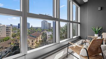 A balcony with a view of a cityscape, wicker furniture, and a potted plant.