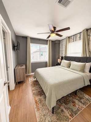 A bedroom with a bed, a nightstand, a ceiling fan, and a window with curtains. - 2BD 2BA Near UH & Downtown, balcony + free parking (Houston)
