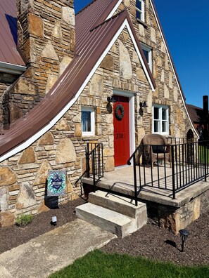 A stone building with a red door, numbered 338, and a welcome sign.