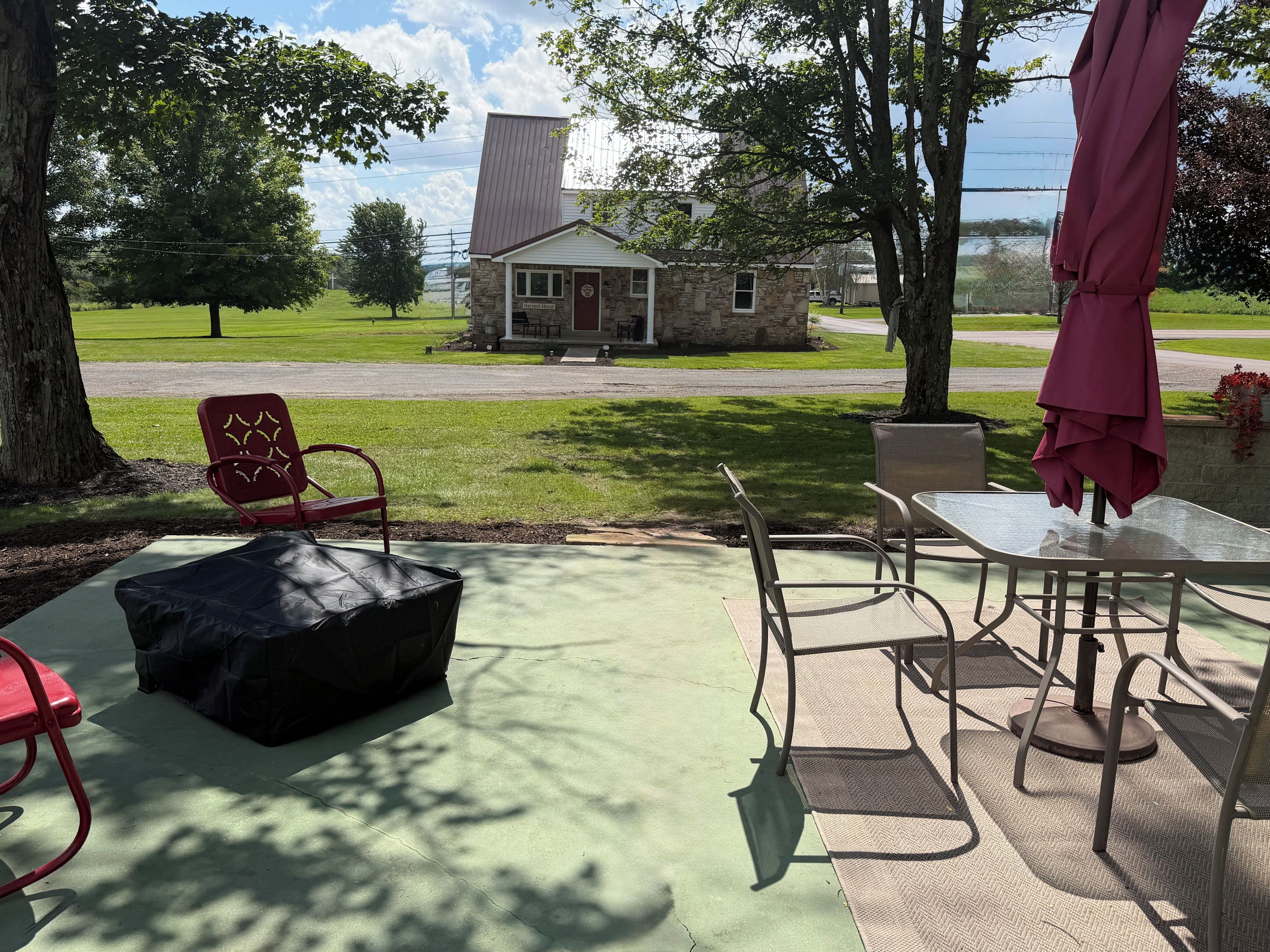 Une terrasse extérieure avec une table et des chaises, un espace salon abrité et une vue sur un bâtiment en pierre en arrière-plan.