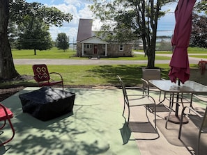 An outdoor patio with a table and chairs, a covered seating area, and a view of a stone building in the background.