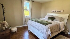 A bedroom with a bed, a window, a nightstand, a lamp, and a decorative wall piece. - Completely remodeled 1 bedroom, with central AC, outdoor area, fully stocked! (Rockwood)