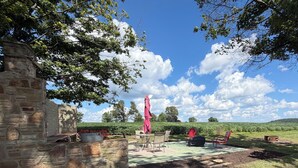 Um edifício de pedra com um pátio, área de estar ao ar livre e vista para um campo.