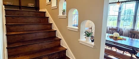 A wooden staircase with built-in shelves and a dining area with a table and benches.