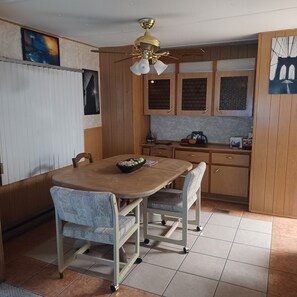 Ruokailutila, jossa on pöytä, tuoleja ja kattotuuletin.