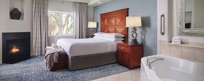 A hotel room with a bed, bedside lamps, a fireplace, a large mirror, and a bathtub. - Walk to WM Phoenix Open & the Bird's Nest! Luxury 1BR Villa (Scottsdale)
