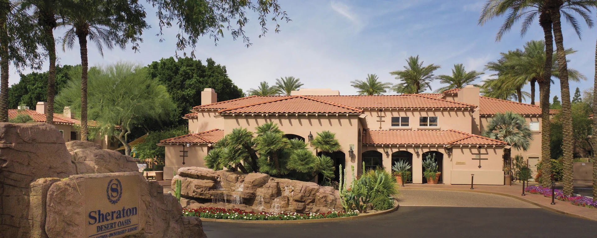 A desert resort with a large building featuring multiple arches and a rock garden.