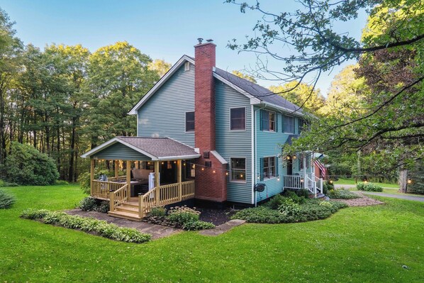 A two-story house with a porch, a brick chimney, and a well-maintained garden.