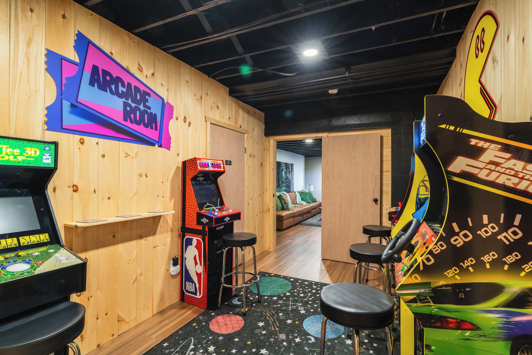 Ein Spielhallenraum mit verschiedenen Spielautomaten, darunter ein Basketballspiel und Rennsimulation.