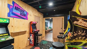 Ein Spielhallenraum mit verschiedenen Spielautomaten, darunter ein Basketballspiel und Rennsimulation.