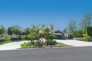A residential street with houses, a driveway, and well-maintained landscaping.