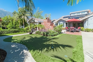 A residential property with a well-maintained lawn, a brick patio, and a covered outdoor seating area.