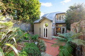 A residential property with a fenced backyard, a small shed, and a house with a sloped roof. - Waterfall Garden 3-Bed Home McMahons Point (McMahons Point)