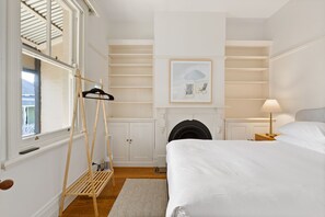 A bedroom with a bed, a hanging chair, a fireplace, and a window with blinds. - Waterfall Garden 3-Bed Home McMahons Point (McMahons Point)