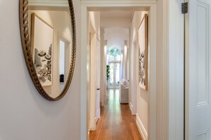 A hallway with a mirror, framed artwork, and a door leading to a room. - Waterfall Garden 3-Bed Home McMahons Point (McMahons Point)