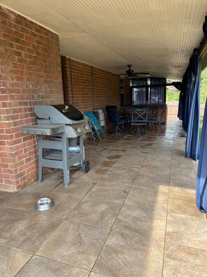 An outdoor covered patio area with a barbecue grill, seating, and a brick wall. - West Knox home w/Hot Tub and Fenced Backyard (Knoxville)