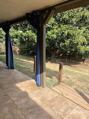 Ein überdachter Patio-Bereich mit Fliesenboden und einem Holzzaun im Hintergrund.
