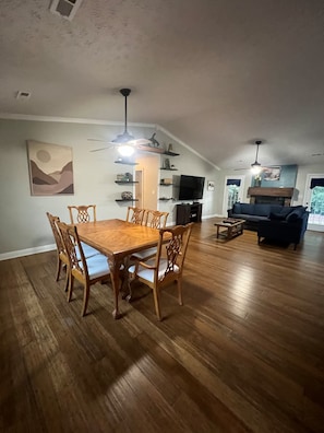 A spacious living area with a wooden dining table, a sofa, and a TV. - West Knox home w/Hot Tub and Fenced Backyard (Knoxville)