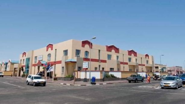 Un edificio a più piani con tetto piatto e un dettaglio rosso sulla sommità.