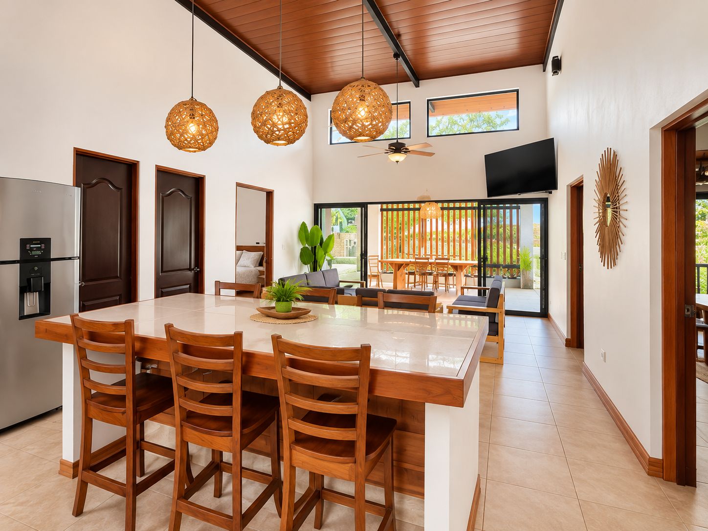 Une cuisine moderne avec un îlot central, des chaises en bois et des luminaires suspendus.