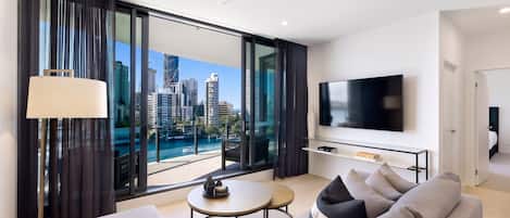 A modern living room with a large window, a flat-screen TV, and a sofa.