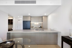 Uma cozinha moderna com ilha central, eletrodomésticos embutidos e mesa de jantar de vidro.