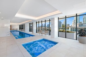 Ein moderner, überdachter Pool mit Whirlpool, großen Fenstern und Blick auf die Stadt.