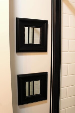 Two black-framed mirrors mounted on a white brick wall. - Uptown Saint John Retreat (Saint John)