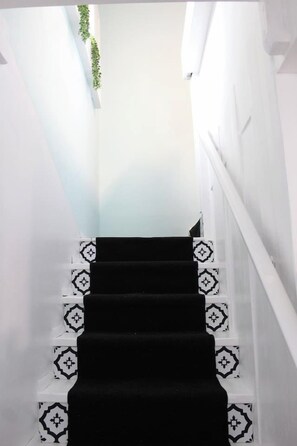 Eine Treppe mit schwarzem Teppich und gemusterten weißen Fliesen.
