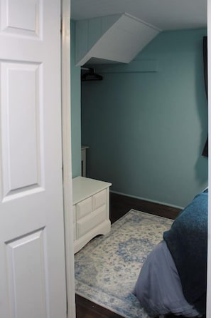 Ein Zimmer mit einer weißen Tür, einer blauen Wand, einem weißen Schminktisch und einem gemusterten Teppich.
