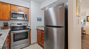 A kitchen with stainless steel appliances, wooden cabinets, and granite countertops. - Royal Kahana | Ocean View Condo, Beach, Pool & West Maui Adventures (Lahaina)