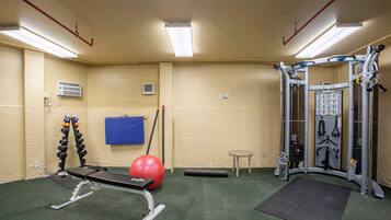 Een fitnessruimte met trainingsapparatuur, een rode trainingsbal en een blauwe mat.