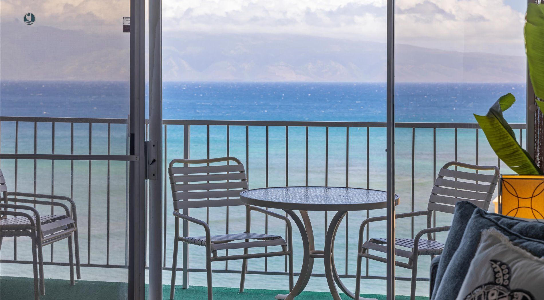 Un balcon avec une table et des chaises, donnant sur une étendue d’eau.
