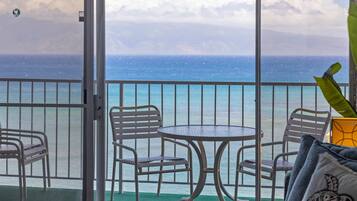 Un balcon avec une table et des chaises, donnant sur une étendue d’eau.