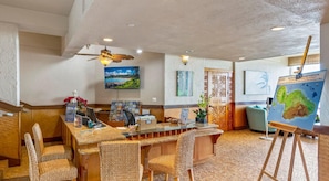 A reception area with a desk, chairs, a map, artwork, and a ceiling fan. - Royal Kahana | Ocean View Condo, Beach, Pool & West Maui Adventures (Lahaina)