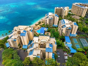 Un grand hôtel avec de nombreux étages, une piscine et un court de tennis.
