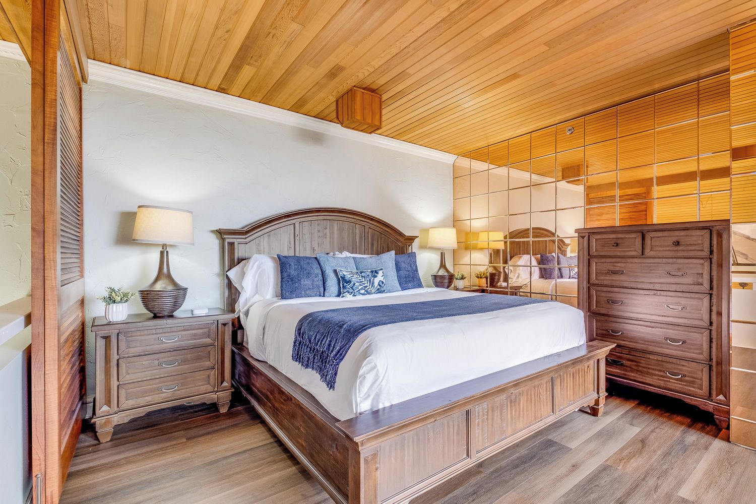 Une chambre à coucher avec un lit en bois, des tables de chevet, une commode et un plafond en bois.