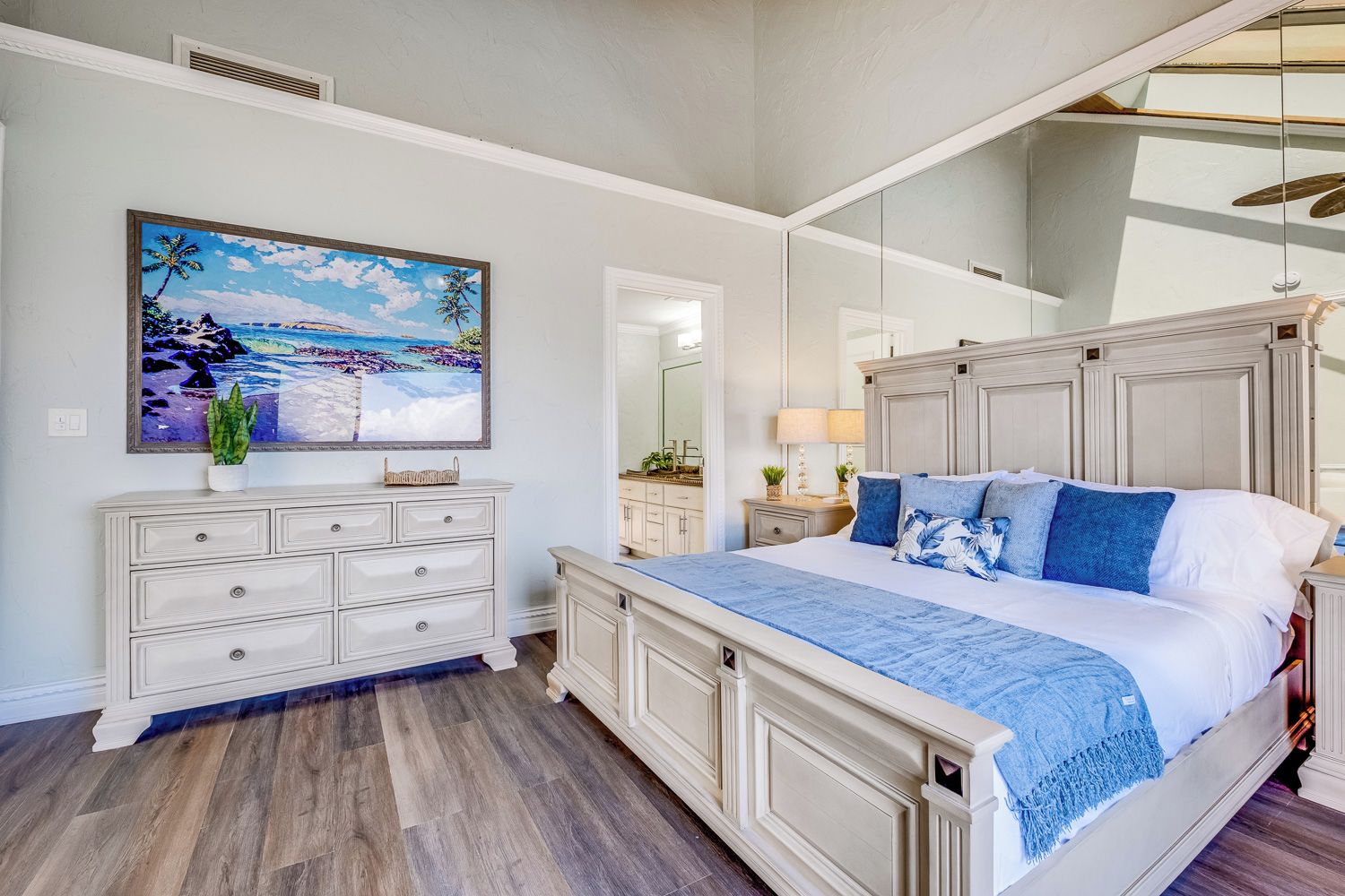 A bedroom with a bed, dresser, and a large mirror.