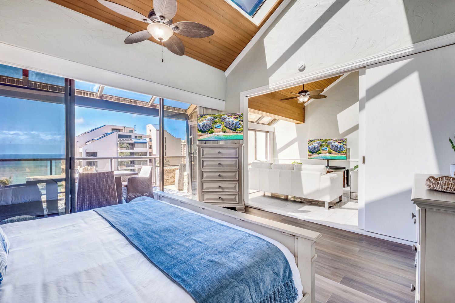 Une chambre à coucher comprenant un lit, une commode, un téléviseur et un balcon avec vue sur la mer.