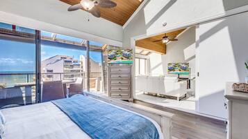 Une chambre à coucher comprenant un lit, une commode, un téléviseur et un balcon avec vue sur la mer.