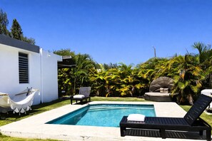 Ein Pool mit Liegestühlen, einer Hängematte und tropischer Bepflanzung.