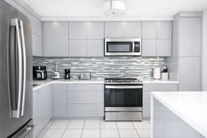 Eine moderne Küche mit Edelstahlgeräten, einer Mikrowelle und einer gefliesten Spritzschutzwand.
