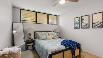 Ein Schlafzimmer mit einem Bett, Nachttischen, einem Deckenventilator und Wandbildern.