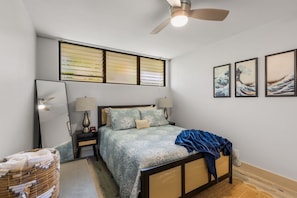 Ein Schlafzimmer mit einem Bett, Nachttischen, einem Deckenventilator und Wandbildern.