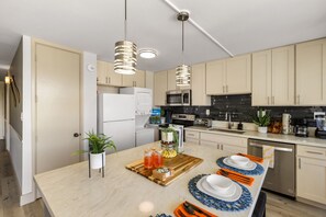 Eine moderne Küche mit weißen Schränken, Edelstahlgeräten und einer zentralen Kochinsel mit einer Holzplatte.