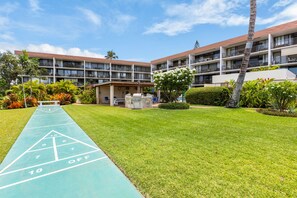 Ein Hotelinnenhof mit Shuffleboardfeld, Sitzgelegenheiten im Freien und üppiger Bepflanzung.