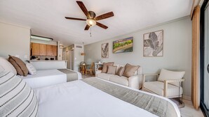 Een hotelkamer met een bed, een bank, een eettafel met stoelen en een plafondventilator.